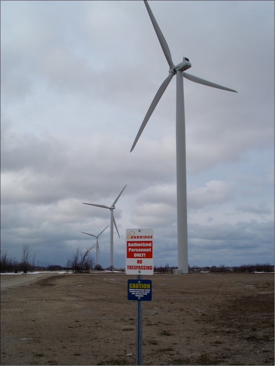 Turbine highway icing caution. Blue Sign Reads “CAUTION – DURING POTENTIAL ICING CONDITIONS STAY BACK 305 METRES FROM TURBINES”